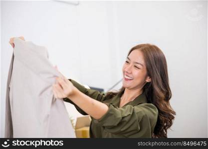 Happy Asian woman customer opening box and looking a new clothes she like it very much, Excited smile female shopper unboxing cardboard box package, shopping online from home, delivery shipping