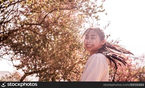 Happy Asian woman enjoying with nature in the park on sunshine day in springtime.