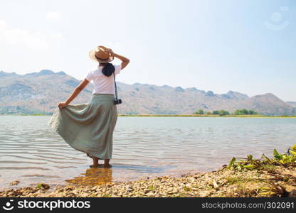 Happy asian woman in casual style clothing standing in the river with mountain view on background