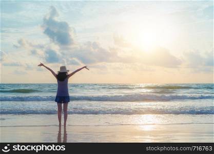 Happy Asian woman relaxing and enjoying at the beach during travel holidays vacation outdoors at ocean or nature sea at sunset time, Phuket, Thailand