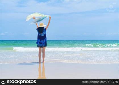 Happy Asian woman relaxing and enjoying at the beach during travel holidays vacation outdoors at ocean or nature sea at noon, Phuket, Thailand