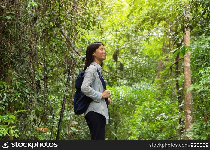 Happy Asian woman relaxing and enjoying at the tropical forest with trees during travel trip and holidays vacation outdoors at national park, Kanchanaburi, Thailand.