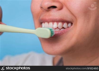 Happy Asian woman taking care of her teeth and holding a toothbrush. Young lady brushing her teeth. dental care and oral hygiene concept.