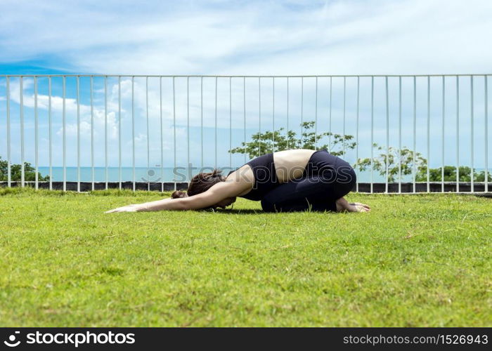 Happy Asian woman wearing black sport wear practice yoga Child pose with beautiful sea view,Feeling relax and comfortable,Healthy Concept