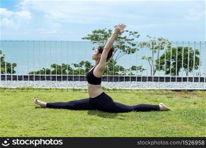 Happy Asian woman wearing black sport wear practice yoga Monkey Pose with beautiful sea view,Feeling relax and comfortable,Healthy Concept