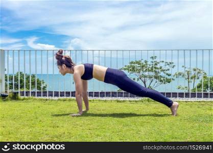 Happy Asian woman wearing black sport wear practice yoga plank on the beach,Feeling relax and comfortable,Healthy Concept