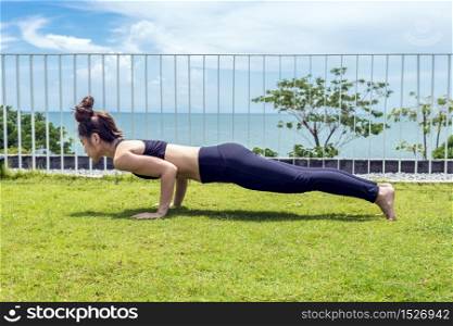 Happy Asian woman wearing black sport wear practice yoga plank on the beach,Feeling relax and comfortable,Healthy Concept