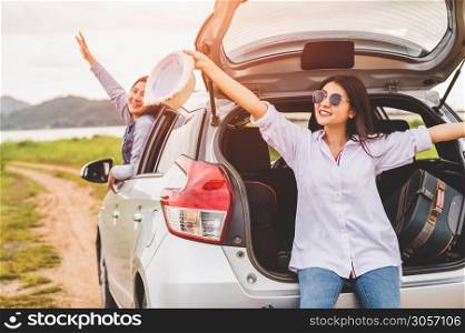Happy Asian women friends spread arms out of window under sunset at seaside with nature background during travel in holiday. Confidence cheerful girl with dawn sky. Sea and mountain. Vacation concept