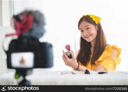 Happy Asian young beauty blogger girl training how to be make up artist in home studio. Woman speaking in front of camera as vlogger. Female vlog blogger recording video tutorial upload to Internet