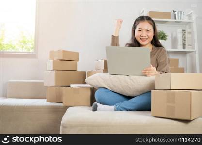 Happy Asian young entrepreneur, Smile for sales success after checking order from online shopping store in laptop at home office, Concept of merchant business online and eCommerce