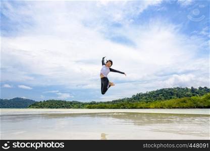 Happy asian young woman wearing sunglasses jumping fun on the beach of Ko Ra Wi on the blue sky by the sea in vacation summer holiday at Lipe island in Tarutao National Park, Satun, Thailand. Happy asian woman jumping fun on the beach