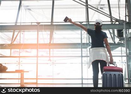 Happy asian young woman with suitcase hands up at the airport