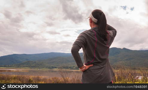 Happy athletic woman resting and looking at the view after running in nature in the morning. Workout Healthy lifestyle concept.