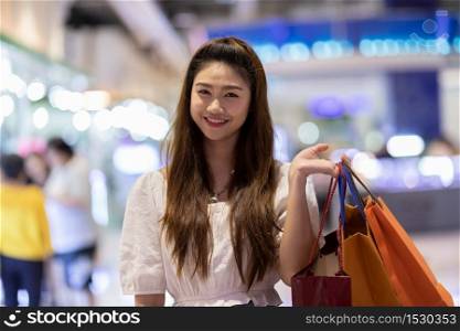 Happy Attractive Asian Woman smile and enjoy with shopping bags in shopping mall,Shopping Concept