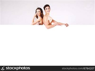 Happy attractive couple naked behind the board
