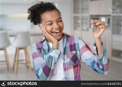 Happy attractive girl rents her first home. Overjoyed young african american woman is holding key from new apartment and moves. Mortgage loan and real estate purchase conceptual image.. Happy girl rents her first home. Overjoyed young african american woman is holding key.