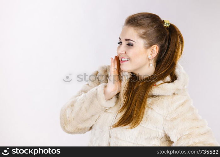 Happy attractive woman wearing light furry warm cozy coat with hood perfect for winter. Cold days fashion concept.. Happy attractive woman wearing furry coat