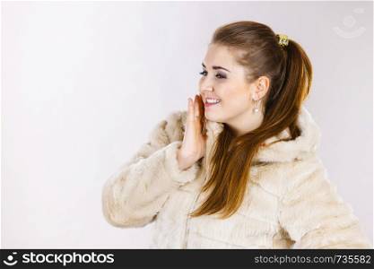 Happy attractive woman wearing light furry warm cozy coat with hood perfect for winter. Cold days fashion concept.. Happy attractive woman wearing furry coat