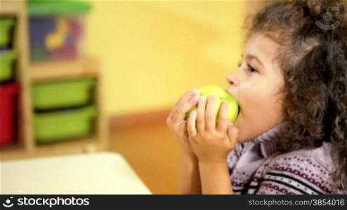 Happy babies and healthy food, female child eating green apple in kindergarten. Sequence