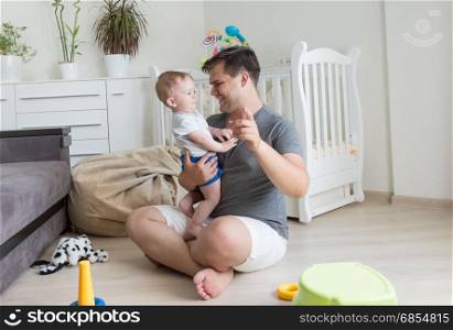 Happy baby boy and young father playing at living room