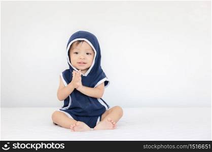 Happy baby boy wearing blue hooded sitting on bed, kids playing concept