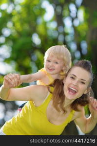 Happy baby girl piggybacking mother