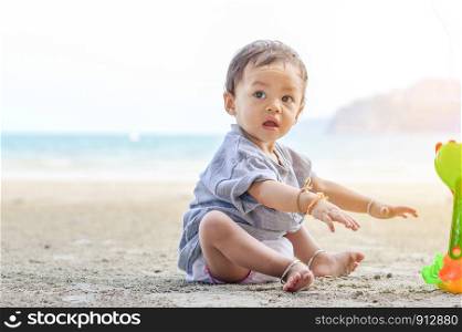 Happy baby girl playing on the sandy beach near the sea