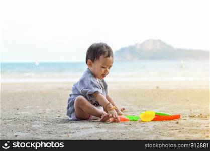 Happy baby girl playing on the sandy beach near the sea