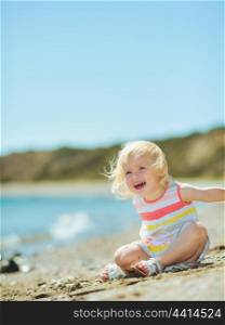 Happy baby girl playing with sand on beach
