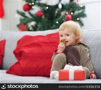 Happy baby in christmas costume eating cookie