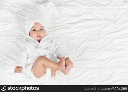 happy baby in soft bathrobe on a bed