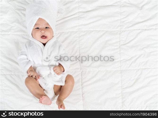 happy baby in soft bathrobe on a bed