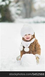 Happy baby making snowball for snowman