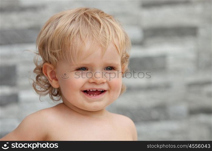 Happy baby one years old with blond and curly hair at outside