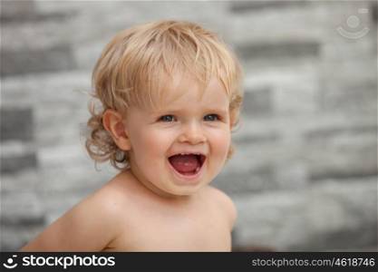 Happy baby one years old with blond and curly hair at outside