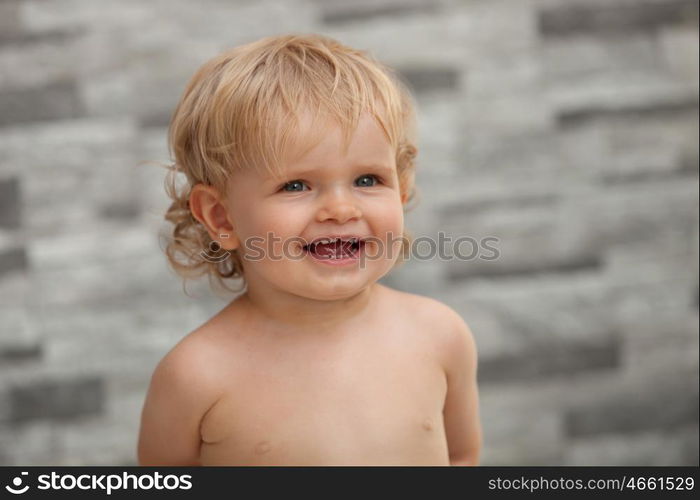 Happy baby one years old with blond and curly hair at outside