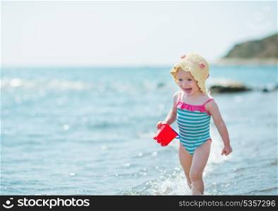 Happy baby running along sea shore