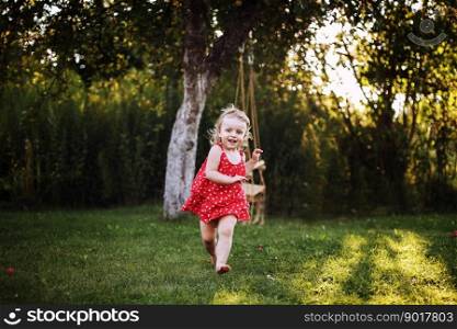 happy baby smiling. a little girl running in the garden at sunset outdoor barefoot. happy baby smiling. little girl running in the garden at sunset outdoor barefoot