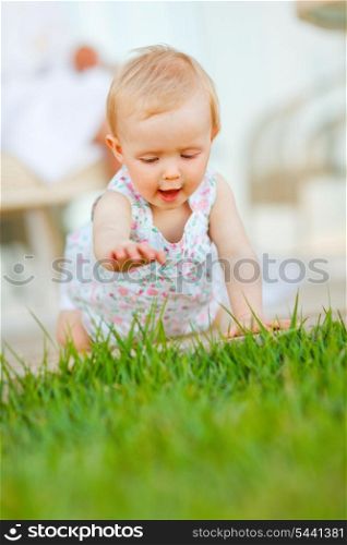 Happy baby trying to touch grass