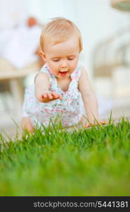 Happy baby trying to touch grass