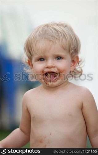 Happy baby with a dirty face after eat chocolate ice