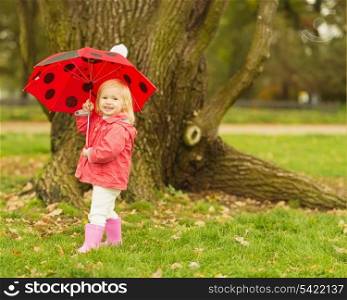 Happy baby with red umbrella outdoors