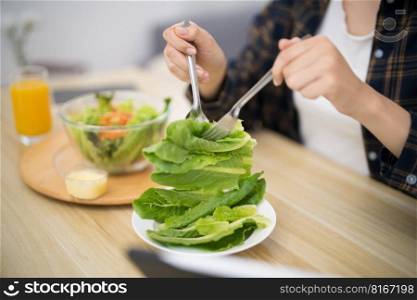 Happy beautiful Asian woman eating healthy food with vegan salad in the kitchen at home. 