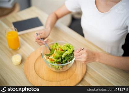 Happy beautiful Asian woman eating healthy food with vegan salad in the kitchen at home. 