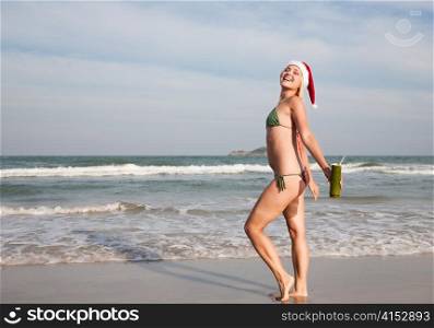 Happy beautiful blond woman in christmas hat on the beach