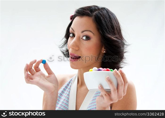 Happy beautiful candy girl with a bowl of colorful bubblegum candy balls licking her lip, isolated