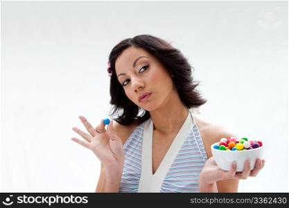 Happy beautiful candy girl with a bowl of colorful bubblegum candy balls thinking, isolated