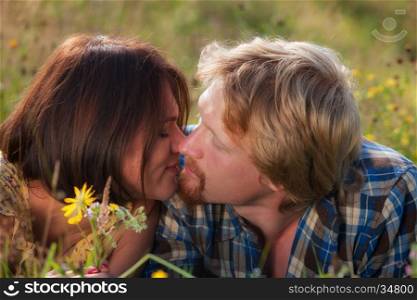 Happy beautiful couple in love kissing on the field