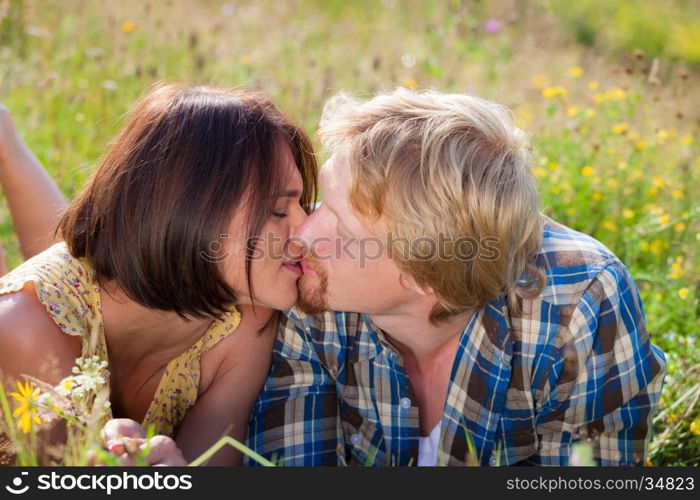 Happy beautiful couple in love kissing on the field