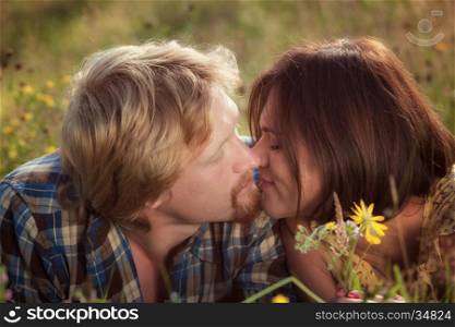 Happy beautiful couple in love kissing on the field